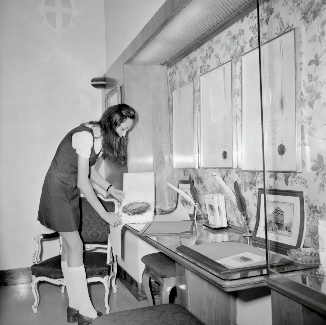 woman in white t-shirt and black pants standing beside table
