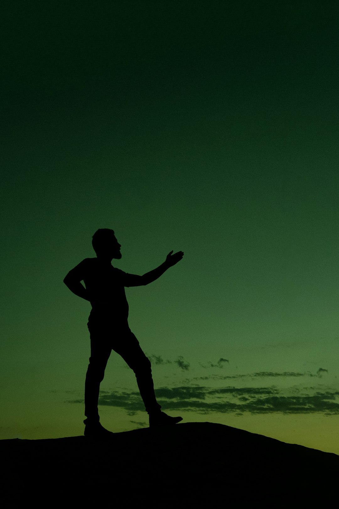 A silhouette of a man standing on top of a hill