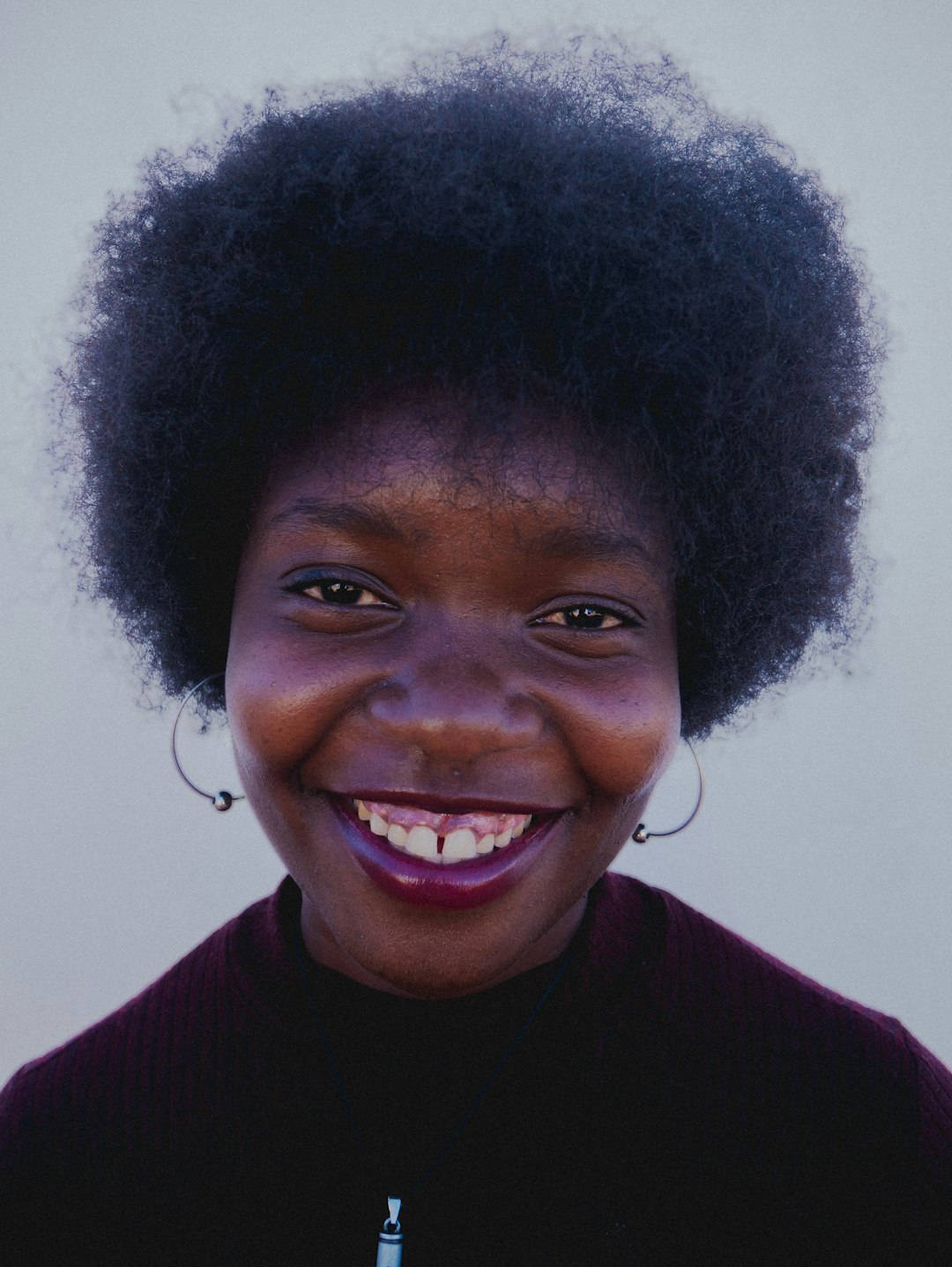 A woman with an afro is smiling for the camera