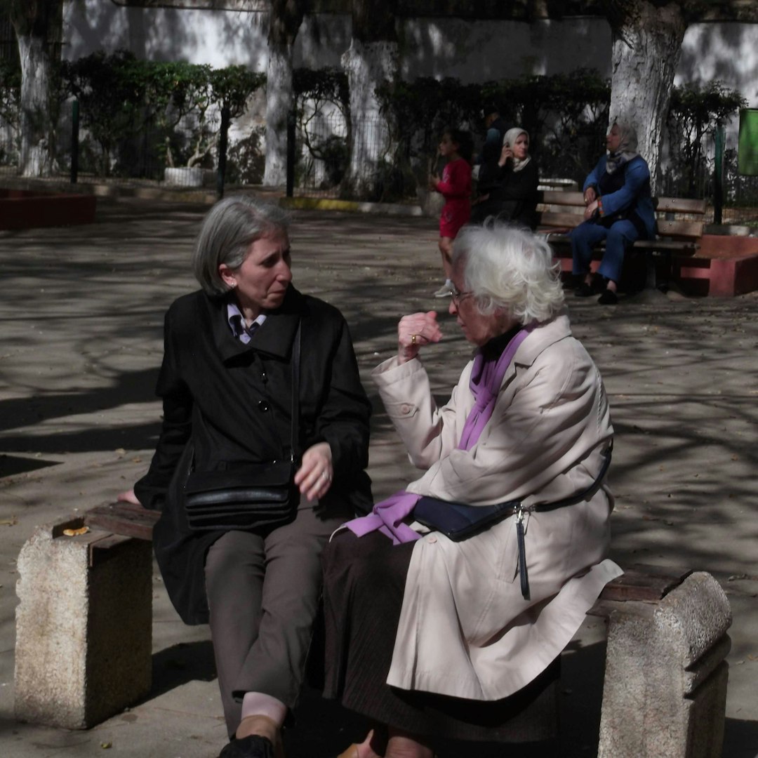 Two elderly women talking on a park bench.