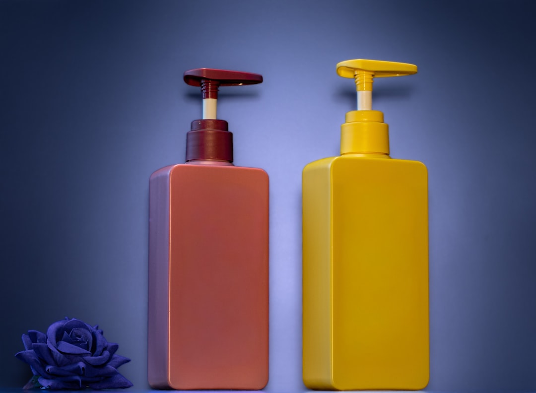 Two pump bottles, one maroon, one yellow, with rose.