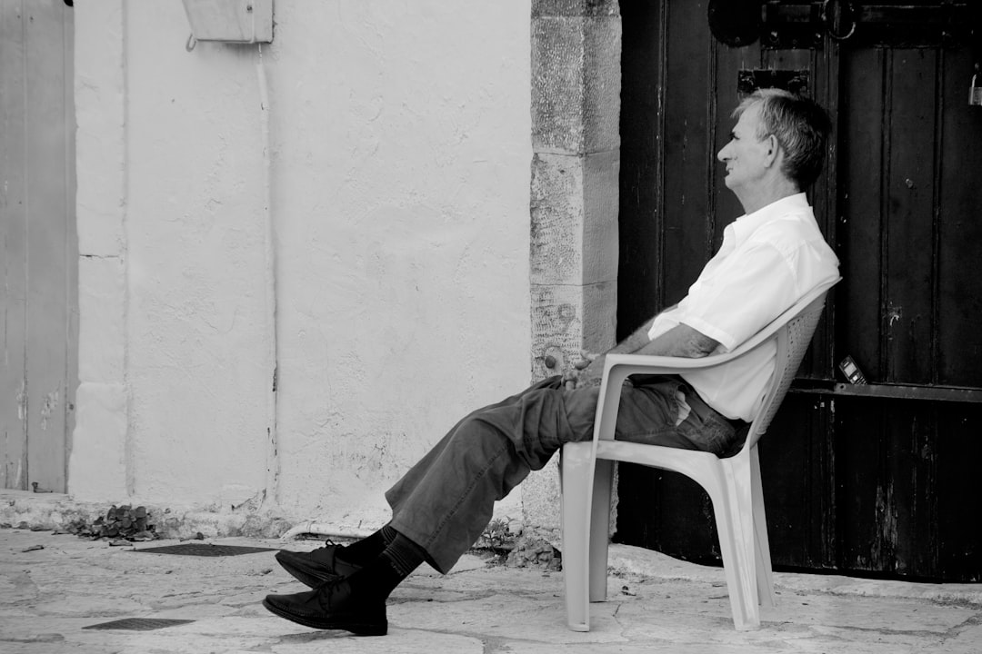 man in white dress shirt sitting on white plastic chair