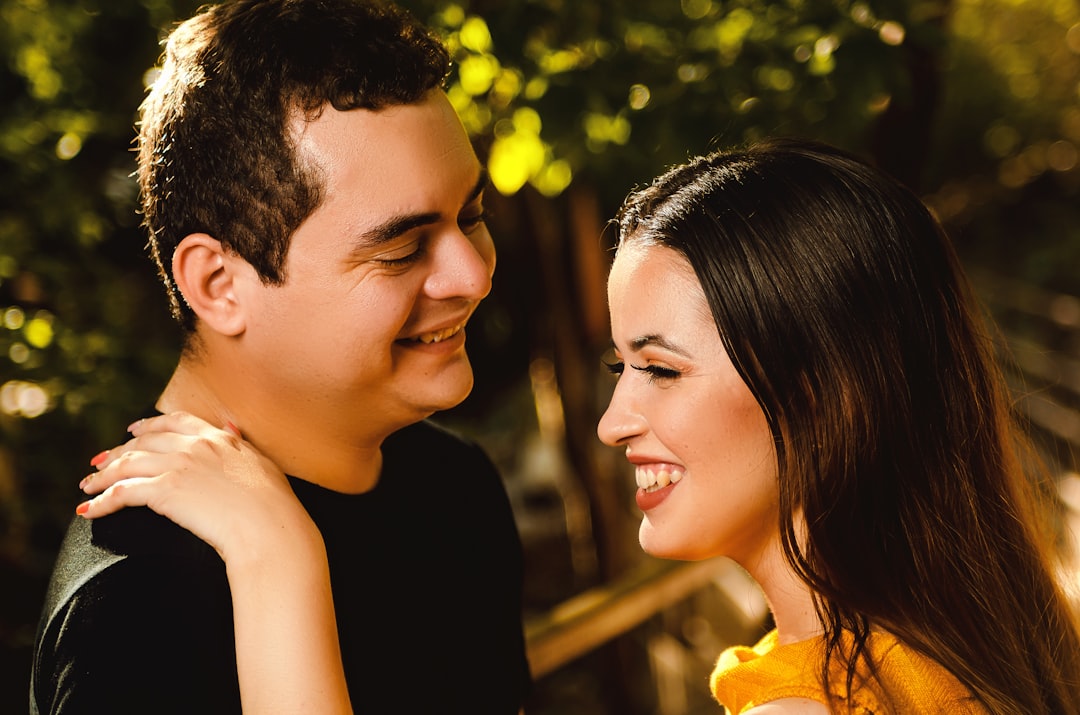 woman in black tank top smiling beside man in yellow shirt