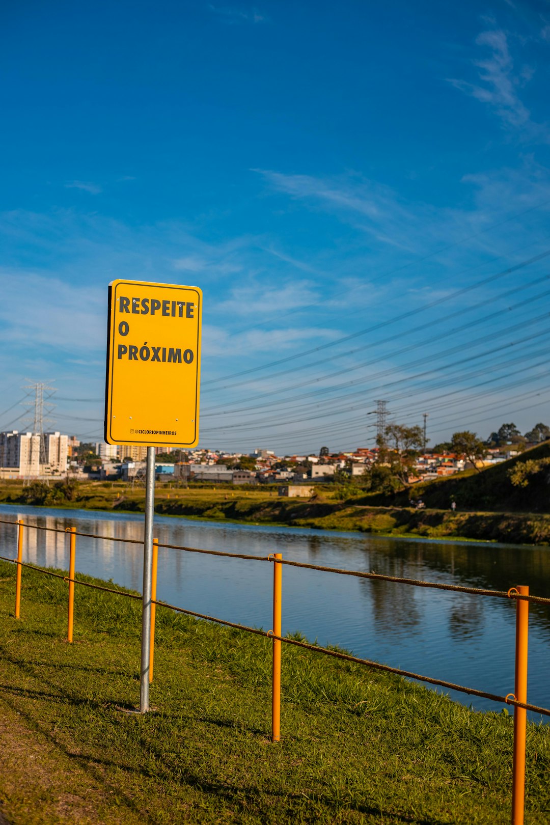 yellow and black road sign near body of water during daytime
