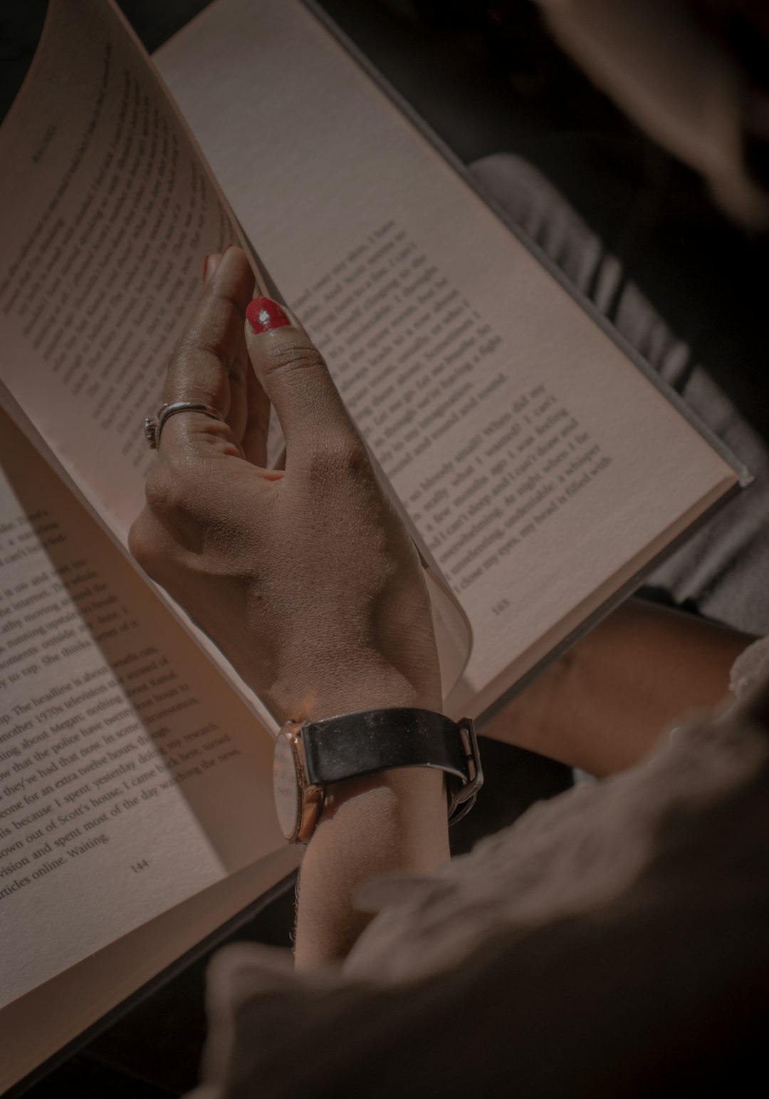 person wearing black leather strap watch reading book