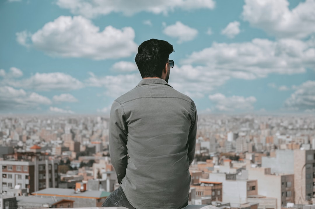 a man sitting on a ledge looking over a city