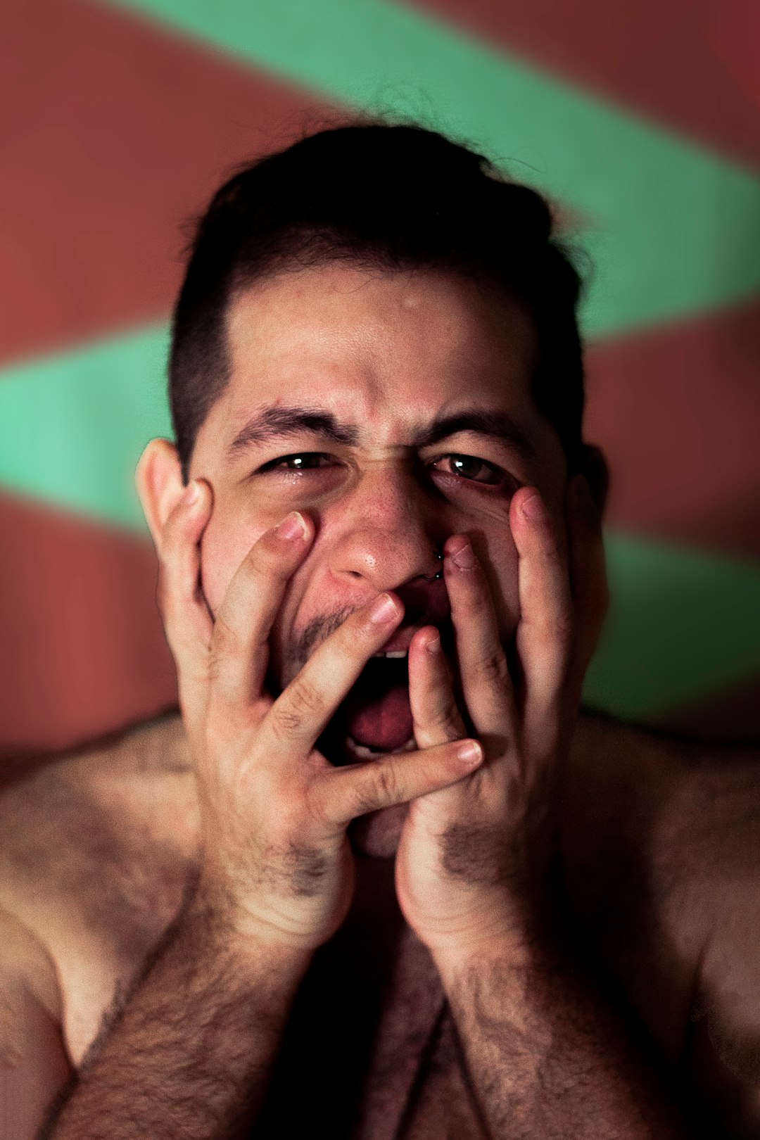 a shirtless man with his hands on his face