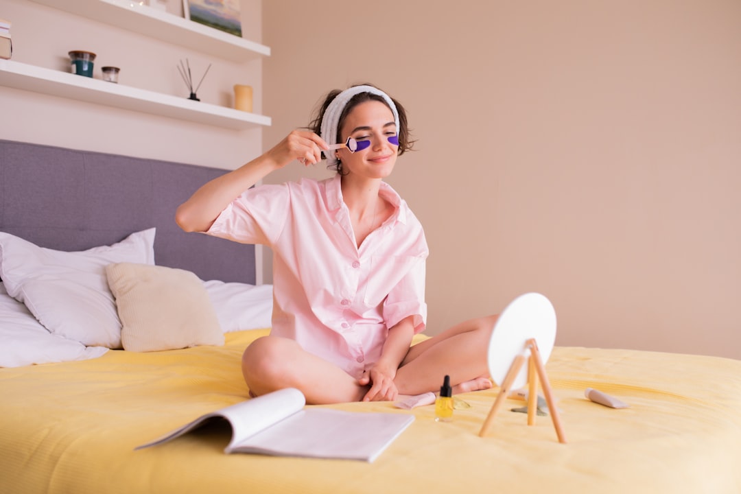 a woman sitting on a bed wearing a pink robe