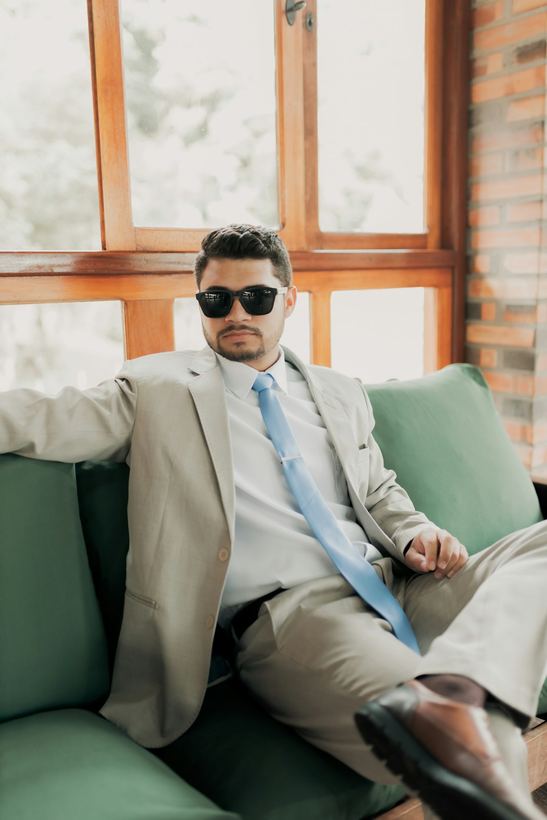 Man in suit and sunglasses relaxes on a couch.