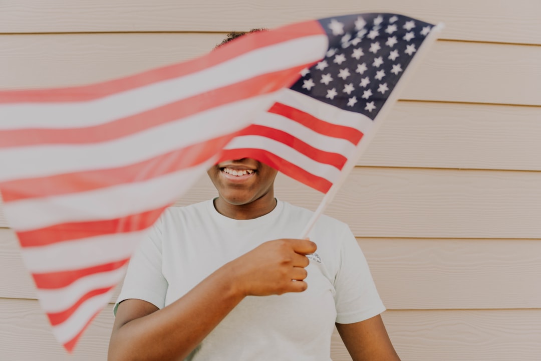 Person holds an american flag, smiling and happy.