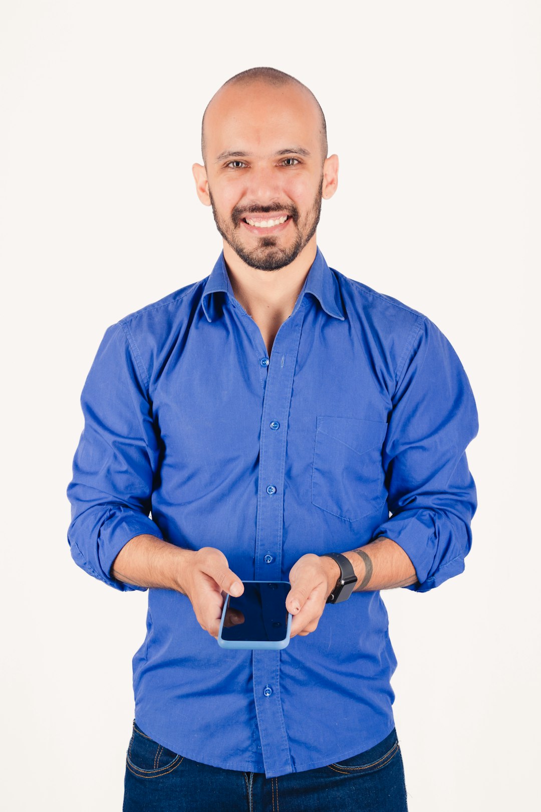 Bald man in blue shirt holding a smartphone