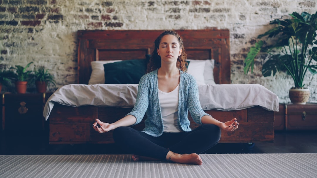 Woman meditating peacefully in a bedroom.