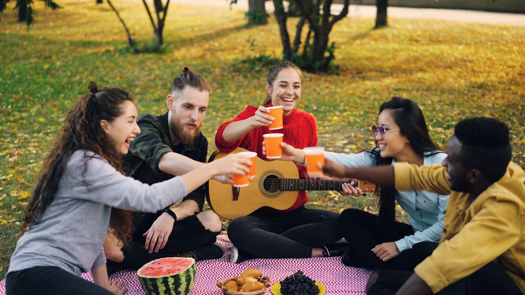 Friends enjoying a picnic and toasting drinks outdoors.