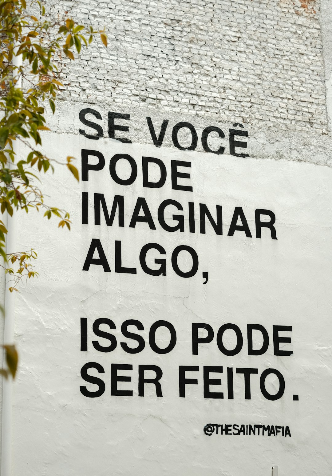 Black text on white wall with inspirational quote.