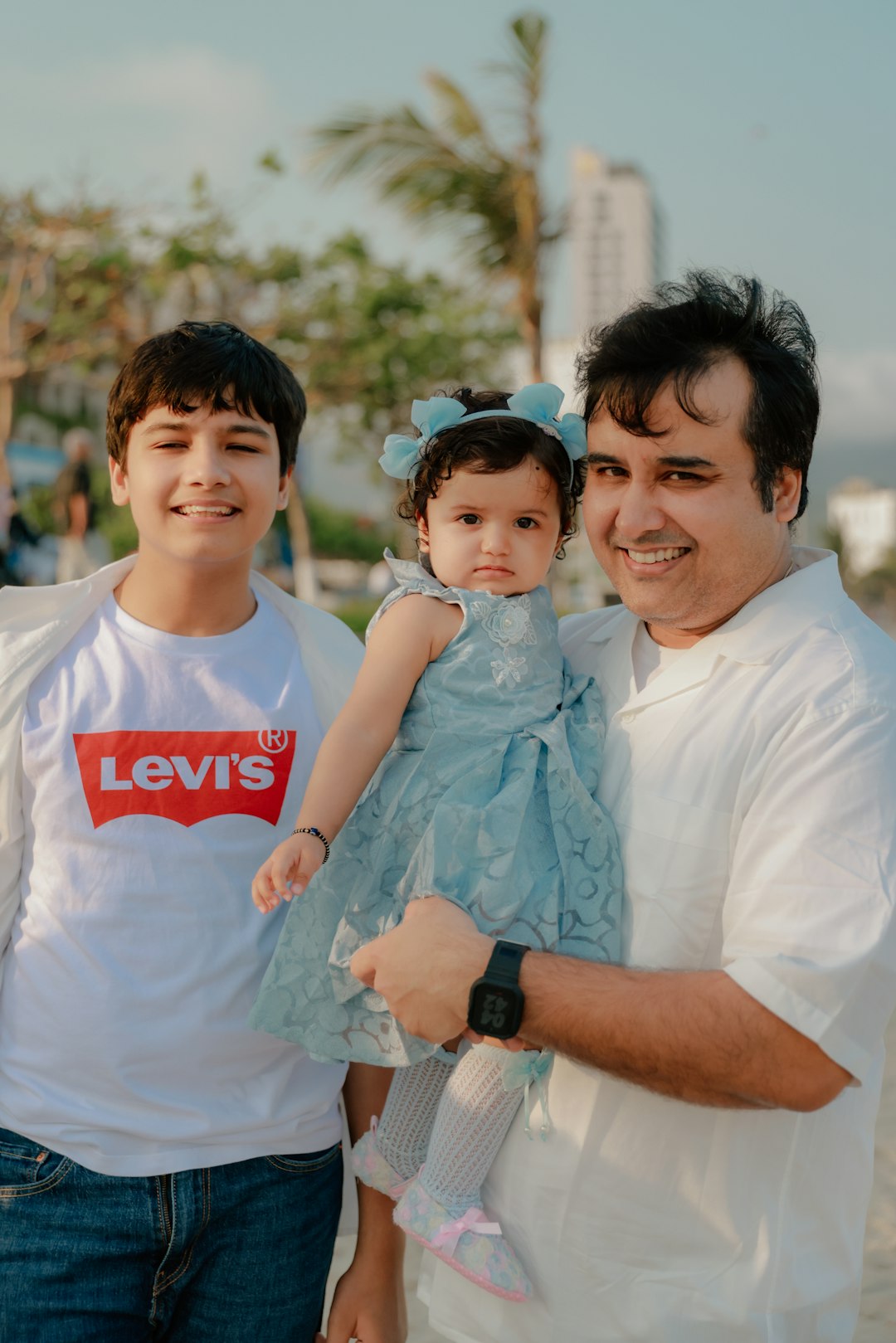 Father holds baby daughter, son stands beside them.